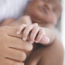 photo of Black mother holding infant's hand