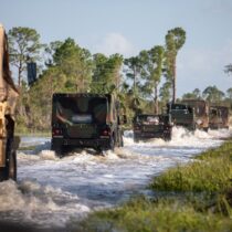 Florida National Guard vehicles mobilizing over a flooded road to provide aid for Hurricane Helene victims.